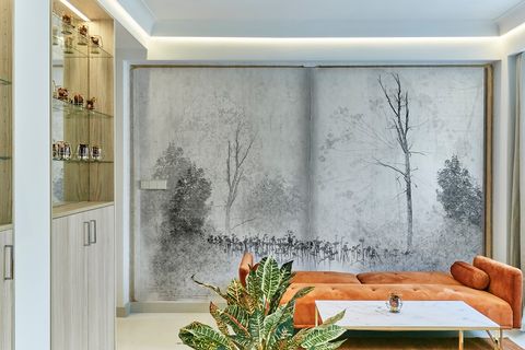 salón con mural inspirado en un paisaje en blanco y negro y sofá naranja de terciopelo